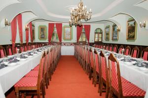 a row of tables in a room with red chairs at Lovecký zámeček in Buchlovice