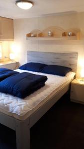 1 dormitorio con 1 cama grande con almohadas azules en Comfortabel 4-persoons chalet (airco + fietsen) op Recreatiepark Eikenhof, en Paasloo