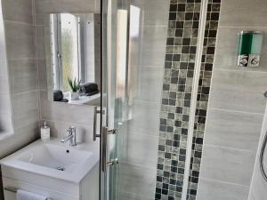 a bathroom with a sink and a shower with a mirror at Levenview Holiday Apartment Loch Lom in Balloch +24 photos
