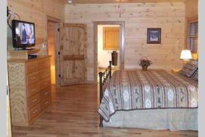 a bedroom with a bed and a dresser with a television at Cherokee Dream Mountain Lodge in Epworth