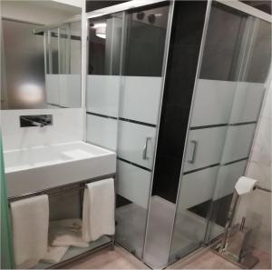 a bathroom with a sink, toilet and shower stall at Hotel Primavera in Amadora