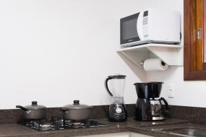 a kitchen counter with two pots on a stove with a microwave at Monte Felice Stay - Parque da Vinícola in Gramado