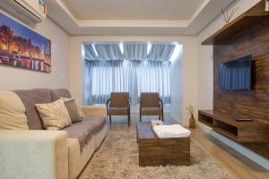 uma sala de estar com um sofá e uma televisão de ecrã plano em Monte Felice Stay - Parque da Vinícola em Gramado