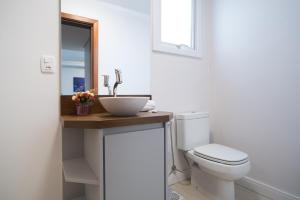 a bathroom with a white toilet and a sink at Monte Felice Stay - Parque da Vinícola in Gramado