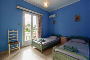 een slaapkamer met 2 bedden, een stoel en een raam bij Mother's House in syros Aegean sea in Posidhonía