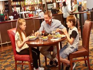 a man and two children sitting at a table eating food at Beautiful Spacious Holiday Home - Romney Sands in New Romney