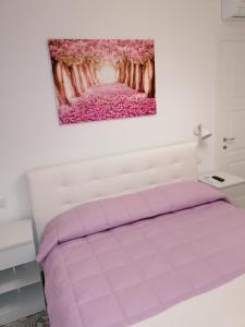 a bedroom with a pink bed with a painting on the wall at La Casa di Pitti in Anacapri