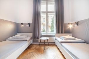 two beds in a room with a window at Dizzy Daisy Hostel in Krakow