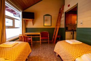 a room with two beds and a table and a kitchen at Tysfjord Hotel in Storjord I Tysfjord