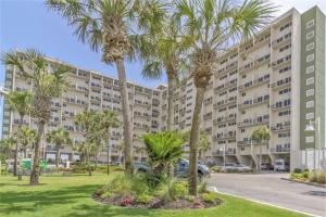 a large apartment building with palm trees in a park at Pinnacle Port Beach Resort in Panama City Beach