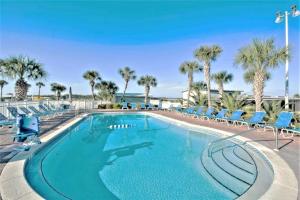 a large swimming pool with chairs and palm trees at Pinnacle Port Beach Resort in Panama City Beach +12 photos