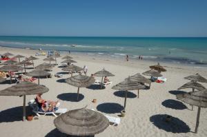 una playa con muchas sombrillas y gente en la playa en Iris Hotel & Thalasso en Taguermess