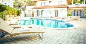 a swimming pool with chairs and a house at Villa Donna Carmela in Pimonte