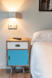 a bedside table with a blue light on it next to a bed at Casa Néboa. in Negreira