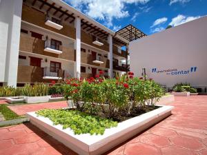 un jardín frente a un edificio con flores rojas en La Alborada en Comitán de Domínguez
