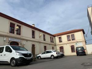 two white cars parked in front of a building at Albergue La Estación in Llanes