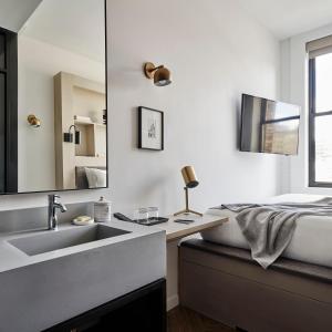 a bathroom with a sink and a bed with a mirror at Walker Hotel Tribeca in New York
