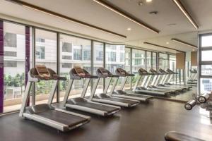 a row of treadmills in a gym with windows at The Robertson Bukit Bintang by Wowhome in Kuala Lumpur
