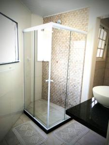 a glass shower in a bathroom with a sink at Hospedagem Doce Lar - Casa Manacá in Teresópolis