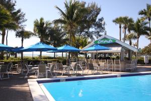 a pool with chairs and umbrellas and a restaurant at Casa Ybel Resort in Sanibel