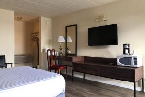 a hotel room with a bed and a desk with a tv at Knights Inn Fort Erie in Fort Erie