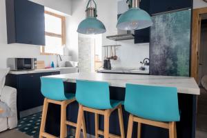 a kitchen with blue chairs at a kitchen island at Penthouse Torre del Mar Grupo AC Gestion in Cádiz