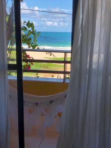 - une fenêtre avec vue sur la plage et l'océan dans l'établissement Ap Beirar Mar com Piscina, à Cabo de Santo Agostinho