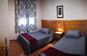 a bedroom with two beds and a window at Hostal Los Hermanos in Baza