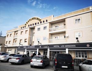 un gran edificio con coches estacionados frente a él en Hostal Los Hermanos en Baza