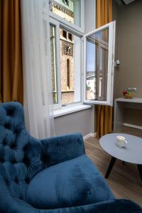 einen blauen Stuhl und einen Tisch in einem Zimmer mit Fenster in der Unterkunft Beys Palace apartments Sarajevo in Sarajevo