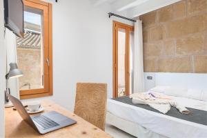 Zimmer mit einem Laptop auf einem Tisch und einem Bett in der Unterkunft Alcudia Petit - Turismo de Interior in Alcúdia