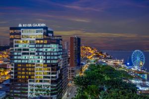 une ligne d'horizon de la ville avec un grand bâtiment et une roue ferris dans l'établissement River Garden Hotel + Suites, à Guayaquil