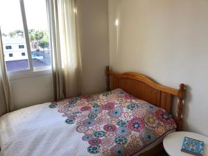 Bett mit einer Decke in einem Zimmer mit Fenster in der Unterkunft Casa Fontana in Cala Ratjada