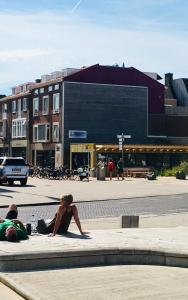 
a person sitting on a bench in front of a building at Nicolette Apartments in Katwijk
