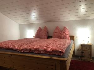 インツェルにあるHaus Annerl Ferienwohnung mit 2 Schlafzimmernのベッドルーム1室(木製ベッド1台、赤い枕付)