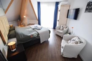 een slaapkamer met een bed, een bank en een stoel bij Table d'Hôte Teune & Janna in Zoutelande