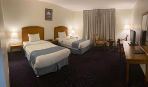 a hotel room with two beds and a desk at Doolve Hotel Al Khobar in Al Khobar