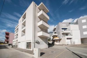 - un bâtiment blanc avec des balcons sur le côté dans l'établissement International apartment Radic, à Makarska