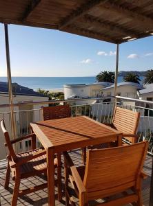 a wooden table and chairs on a balcony with the ocean at Onetangi Beach Apartments in Onetangi