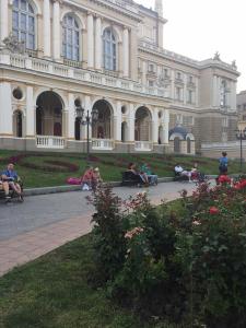 a group of people sitting on benches in front of a building at Красивая 2-ком.кв.,в Новом доме!От хозяйки! in Odesa