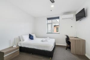 Dormitorio con cama, escritorio y TV en Alloggio Studios on King en Newcastle