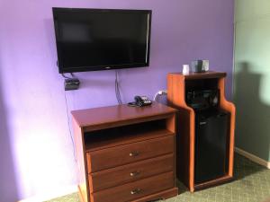 a tv on a purple wall with a wooden dresser and a dressererness at Western Inn Roswell in Roswell