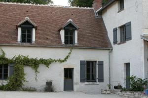 a white house with black windows and a brown roof at Le Petit Moulin in Faverelles