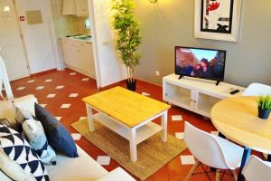 uma sala de estar com uma televisão e uma mesa e cadeiras em Baluarte da Vila Apartments em Lagos