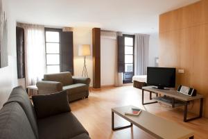 a living room with a couch and a tv at Aspasios Plaza Real Apartments in Barcelona