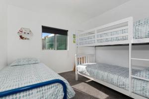 ein Schlafzimmer mit zwei Etagenbetten und einem Fenster in der Unterkunft The Sunshine Bungalow - Mangawhai Heads Home in Mangawhai