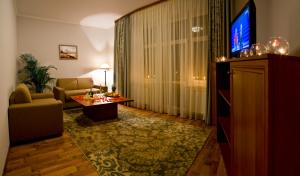 ein Wohnzimmer mit einem TV, einem Sofa und einem Tisch in der Unterkunft Hotel Re Vita in Truskawez