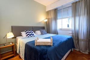 a bedroom with a bed with a blue blanket and a window at Espaçoso 3Qtos no Leblon com Garagem | BM 647/405 in Rio de Janeiro