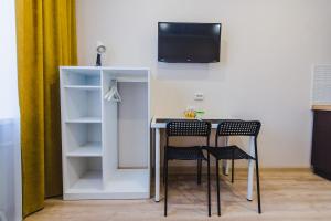 a table with two chairs and a tv on a wall at Dekabrist Apartment Nabereshnaya 66 in Chita