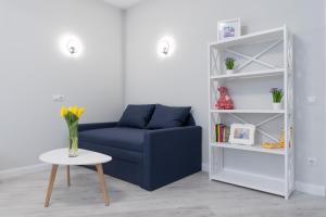 ein Wohnzimmer mit einem blauen Sofa und einem weißen Regal in der Unterkunft Красивая 1 комнатная квартира с балконом на Теремках 252 in Kiew